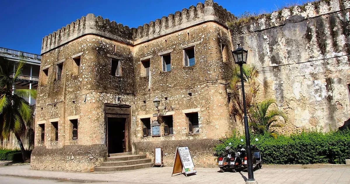 The coral-stone walls of the Old Fort in Stone Town, with the tour board and scooters at its door.